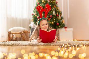 Little girl reading a book at home on Christmas day